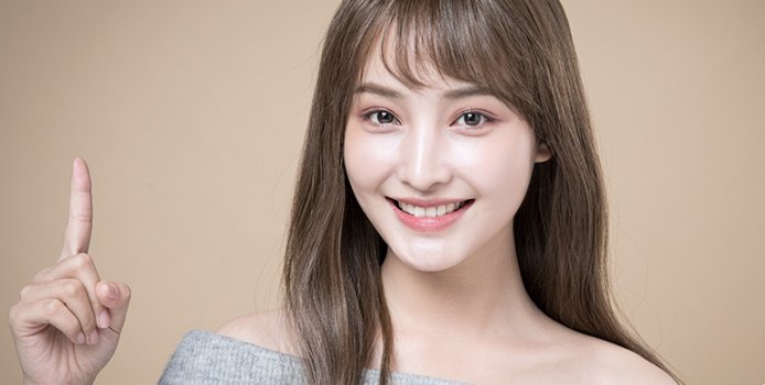 환하게 웃으며 손가락을 든 여성